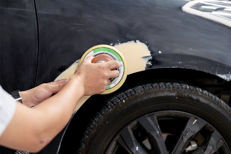 Technician sanding automotive body filler