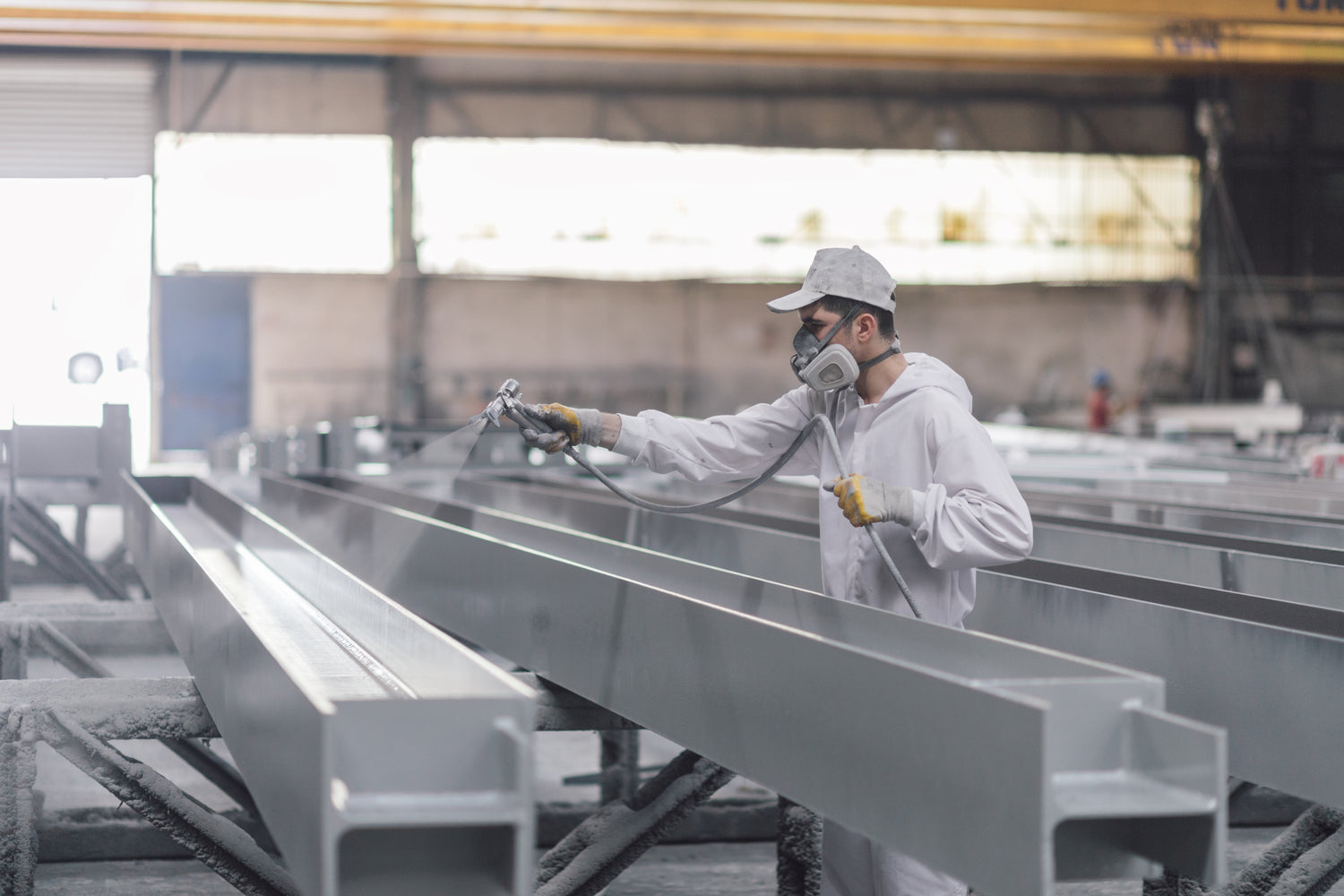 Worker applying industrial protective coating to steel beams