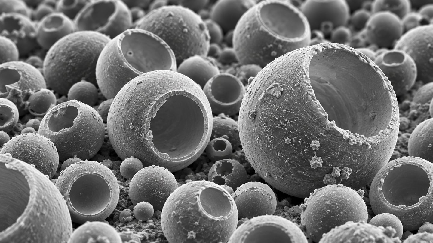Grayscale SEM style illustration of hollow microspheres and shells